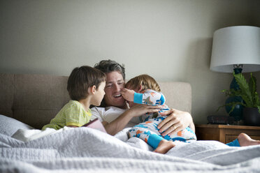 Glücklicher Vater entspannt sich mit seinen Söhnen auf dem Bett zu Hause - CAVF03226