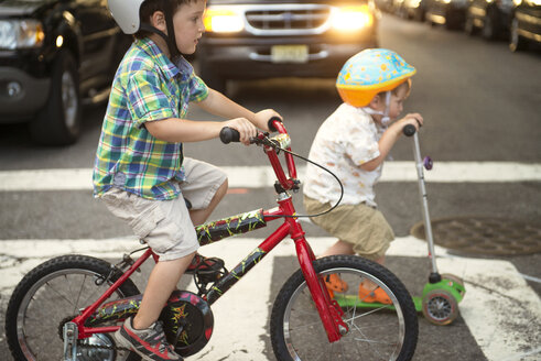 Brothers riding push scooter and bicycle on road - CAVF03240