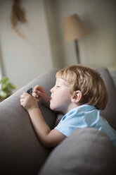 Junge spielt mit Spielzeug auf dem Sofa zu Hause - CAVF03242