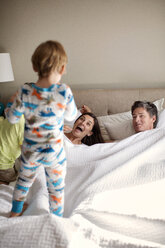 Glückliche Eltern betrachten ihren Sohn auf dem Bett - CAVF03255