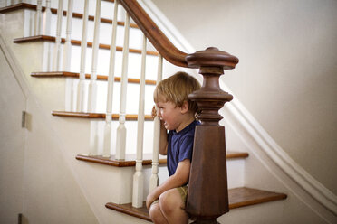 Junge weint auf der Treppe sitzend zu Hause - CAVF03262