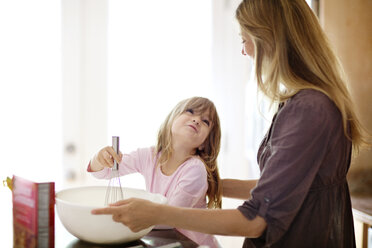 Cute girl looking at mother while baking at home - CAVF03269