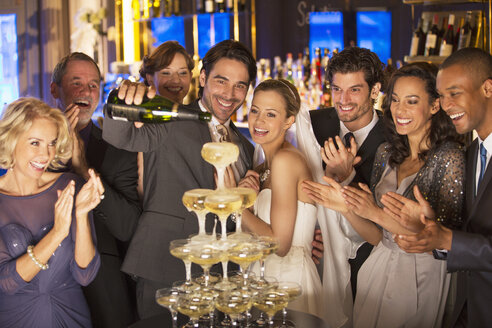 Braut und Gruppe gießen Champagner-Pyramide bei der Hochzeitsfeier - CAIF08136