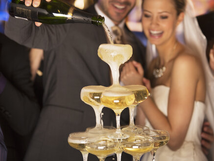 Bräutigam gießt Champagner-Pyramide bei der Hochzeitsfeier - CAIF08151