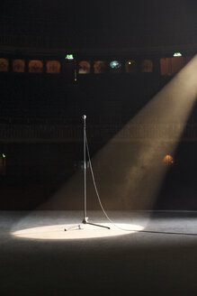Mikrofon im Scheinwerferlicht auf leerer Theaterbühne - CAIF08227