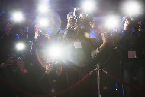 Paparazzi fotografieren mit Blitzlicht bei einer Veranstaltung auf dem roten Teppich, lizenzfreies Stockfoto