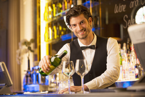 Porträt eines gut gekleideten Barkeepers, der in einer Luxusbar Wein einschenkt - CAIF08247