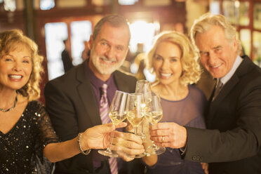 Portrait of well dressed couples toasting champagne flutes in theater lobby - CAIF08266