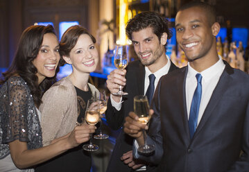 Portrait of well dressed couples toasting champagne flutes - CAIF08277