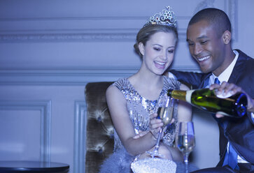 Mann schenkt Champagner für Frau mit Diadem ein - CAIF08287