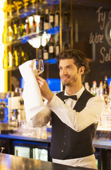 Gut gekleideter Barkeeper wischt Weinglas in einer Luxusbar ab - CAIF08321