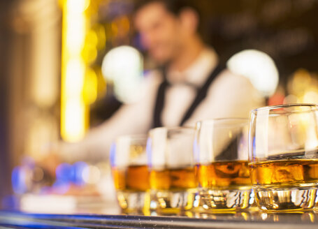 Nahaufnahme von Bourbon in Gläsern in einer Reihe auf der Bar - CAIF08325