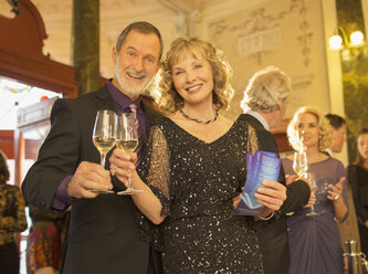 Portrait of well dressed couple toasting champagne flutes in theater lobby - CAIF08345