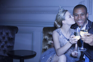 Gut gekleidetes Paar, das sich küsst und mit Champagnerflöten anstößt - CAIF08379