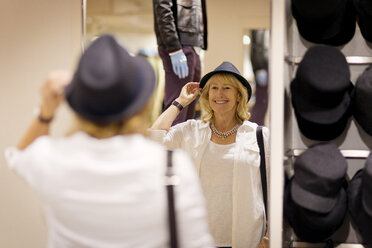 Fröhliche Frau mit Hut in einem Bekleidungsgeschäft - CAVF03335