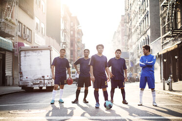 Confident soccer players standing at city street against clear sky - CAVF03359