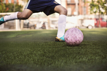 Niedriger Ausschnitt eines Sportlers, der einen Ball auf einem Fußballplatz kickt - CAVF03366