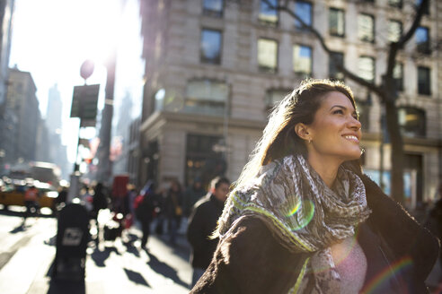 Lächelnde Frau, die beim Gehen auf dem Fußweg in der Stadt nach oben schaut - CAVF03535