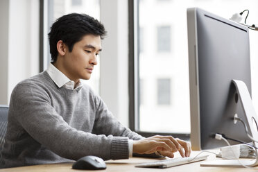 Mann arbeitet an einem Desktop-Computer im Büro - CAVF03612