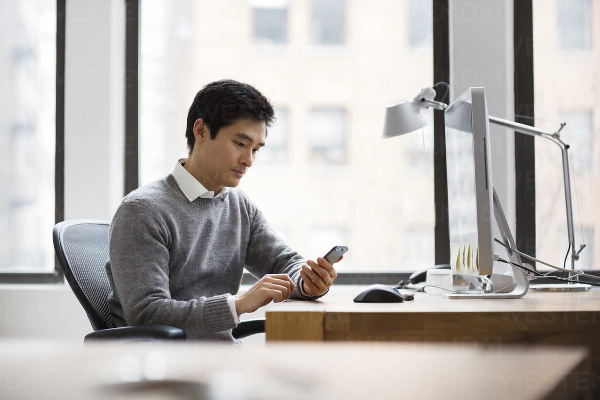 Man using smart phone while working in office stock photo