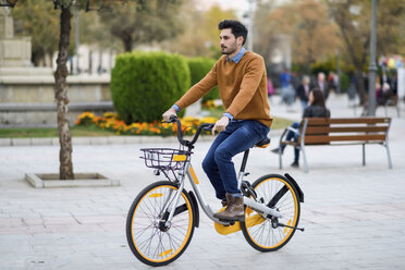 Young man riding rental bike in the city - JSMF00107