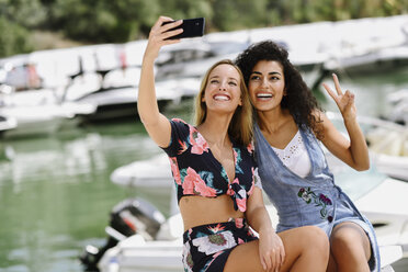 Zwei glückliche junge Frauen machen ein Selfie am Yachthafen im Sommer - JSMF00113