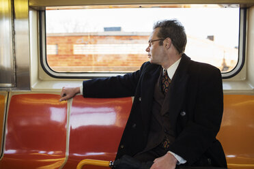 Geschäftsmann schaut weg, während er im Zug sitzt - CAVF03647