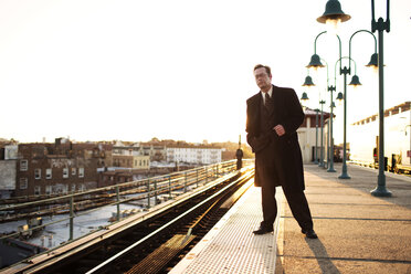 Businessman waiting for train at subway station against clear sky - CAVF03659