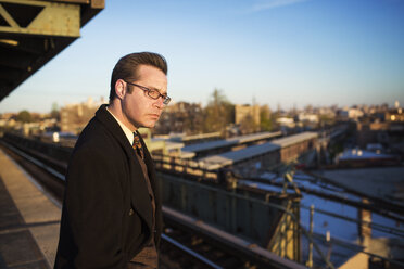 Businessman waiting for train at subway station - CAVF03660