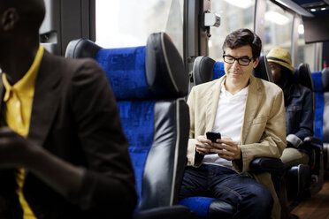 Man using smart phone while sitting in bus - CAVF03692