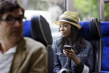 Frau schaut weg, während sie im Bus ein Mobiltelefon benutzt - CAVF03693