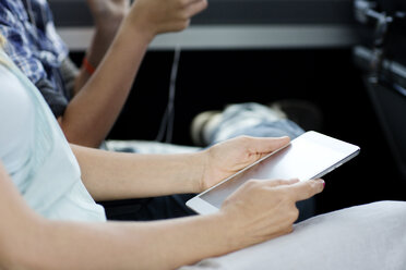Ausgeschnittenes Bild einer Frau, die einen Tablet-Computer hält, während sie mit ihrem Sohn im Bus sitzt - CAVF03712