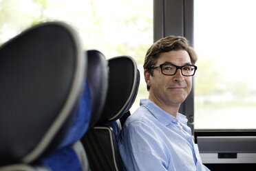 Portrait of man with eyeglasses sitting in bus - CAVF03717