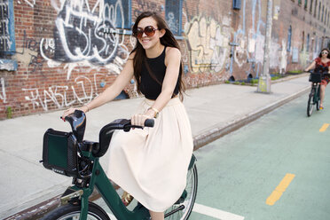 Happy friends riding bicycle on street - CAVF03755