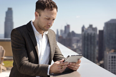 Geschäftsmann mit Tablet-Computer auf der Terrasse eines Gebäudes - CAVF03771