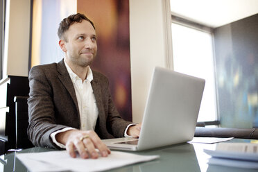 Businessman using laptop computer while sitting at desk - CAVF03777