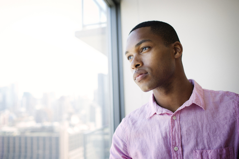 Thoughtful businessman looking through office window stock photo