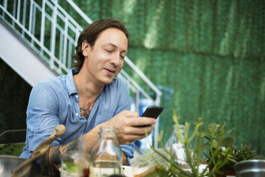 Man looking at mobile phone at backyard - CAVF03874