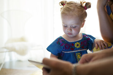Baby-Mädchen schaut auf Tablet-Computer mit Mutter zu Hause - CAVF03885