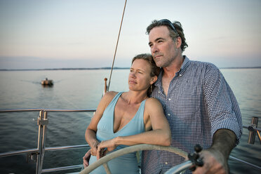 Couple looking away while steering yacht - CAVF03947