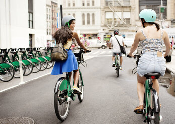 Friends riding bicycle on city street - CAVF03979