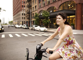 Glückliche Frau fährt Fahrrad in der Stadt - CAVF03996
