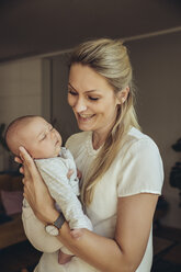 Smiling mother holding sleepy newborn baby - MFF04390