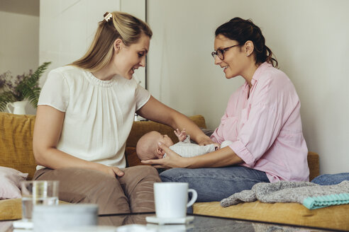 Midwife and mother giving newborn baby a belly massage to help with digestion - MFF04395