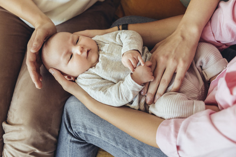 Hebamme und Mutter geben ihrem Neugeborenen eine Bauchmassage, um die Verdauung zu fördern, lizenzfreies Stockfoto