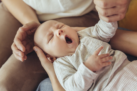 Hebamme und Mutter untersuchen das schläfrige Neugeborene, lizenzfreies Stockfoto