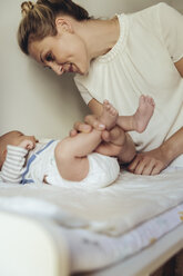 Mother smiling at newborn baby on changing table - MFF04403