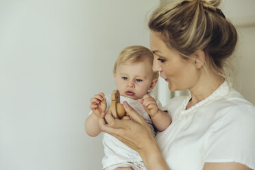 Mother showing her baby a wooden toy - MFF04414