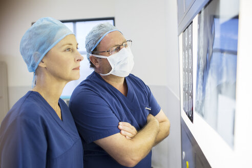 Zwei Ärzte besprechen die Röntgen- und MRT-Aufnahmen eines Patienten vor der Operation - CAIF08427