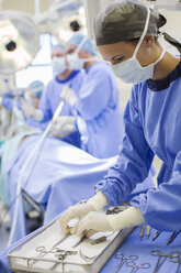 Krankenschwester steht neben einem Tablett mit chirurgischen Instrumenten im Operationssaal - CAIF08429